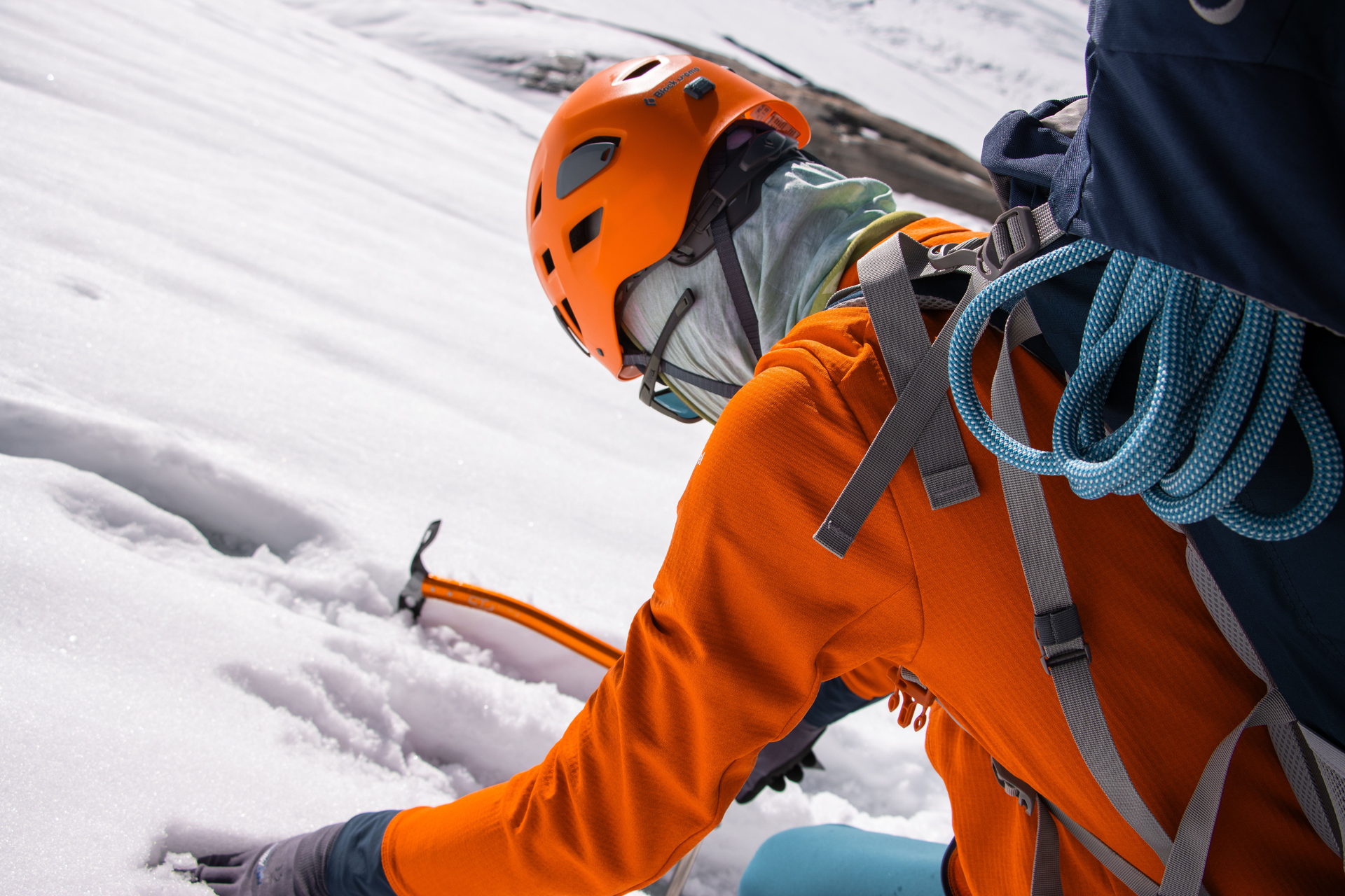 Operador con casco y arnés y piolet clavado en la nieve